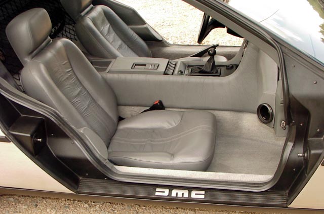 Interior de un DeLorean con tapicería de color gris y caja de cambios manual